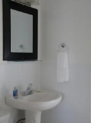 a bathroom with a white sink and a mirror at Driftwood by the Sea Inn in Campbell River