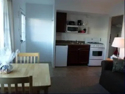 a living room with a table and a kitchen at Driftwood by the Sea Inn in Campbell River