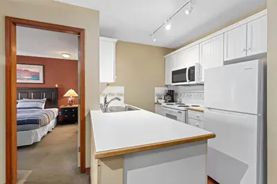 a kitchen with a white refrigerator next to a bed at The Aspens by Whistler Premier in Whistler