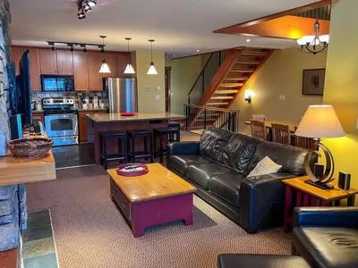 a living room with a leather couch and a kitchen at Pinnacle Ridge Condos by Fernie Central Reservations in Fernie