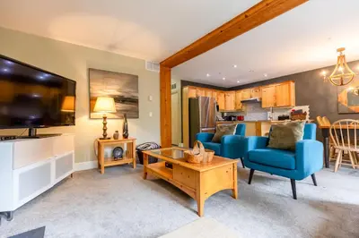 a living room with a blue couch and a table at Ski In & 15 Minute Walk to the Lifts Hot Tub AC Pet Friendly in Fernie