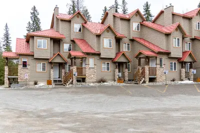 a large house with red roof with a parking lot at Ski In & 15 Minute Walk to the Lifts Hot Tub AC Pet Friendly in Fernie
