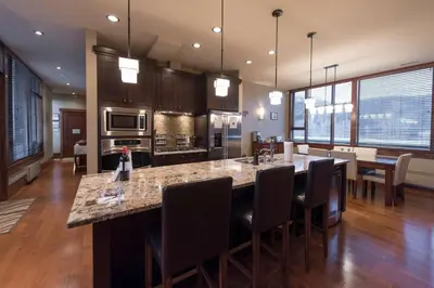 a kitchen with a large island with bar chairs at Luxurious 901 Condos by Fernie Central Reservations in Fernie