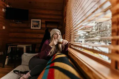 a woman sitting on a couch holding a cup of coffee at Riverside Resort in Whistler