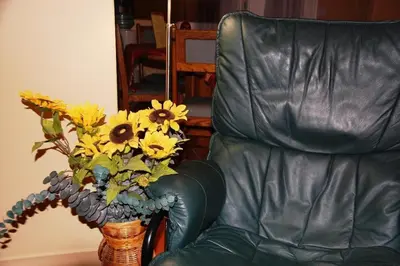 a vase of sunflowers sitting next to a leather chair at A Vacation Paradise at Quail Ridge B&B in Kelowna