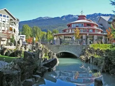 a bridge over a river in front of a building at Studio suite located in the heart of Whistler village in Whistler