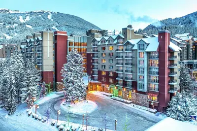 a large building in the snow with a tree in front at Hilton Whistler Resort & Spa in Whistler