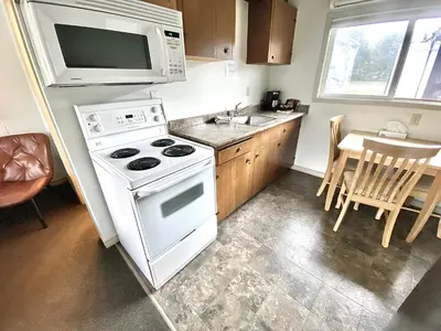 a kitchen with a white stove and a microwave at Arbutus Grove Motel in Parksville