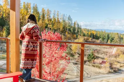 a woman standing on a balcony looking out at a tree at Myra Canyon Guest Ranch in Kelowna