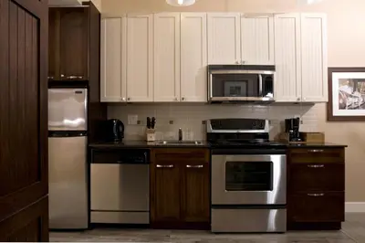 a kitchen with white cabinets and stainless steel appliances at Summerland Waterfront Resort & Spa in Summerland