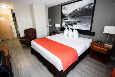 a hotel room with a large bed and a chair at Super 8 by Wyndham Drayton Valley in Drayton Valley