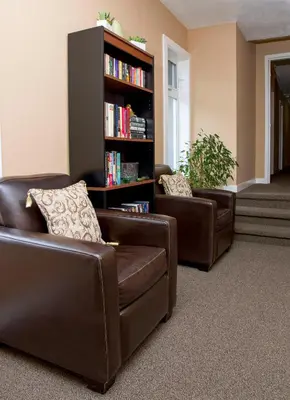 two brown leather chairs and a book shelf with books at Hotel Squamish in Squamish