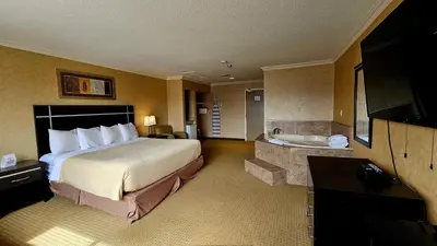 a hotel room with a bed and a bath tub at The George Dawson Inn & Conference Centre in Dawson Creek