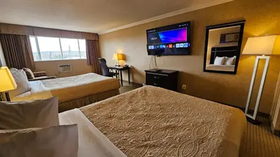 a hotel room with two beds and a flat screen tv at The George Dawson Inn & Conference Centre in Dawson Creek