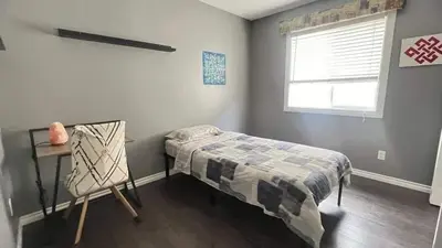 a bedroom with a bed and a desk and a window at Monthly Accommodation Edmonton Londondery, Pilot Sound, McConachie Area in Edmonton