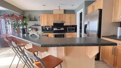 a kitchen with a black counter top and wooden cabinets at Monthly Accommodation Edmonton Londondery, Pilot Sound, McConachie Area in Edmonton