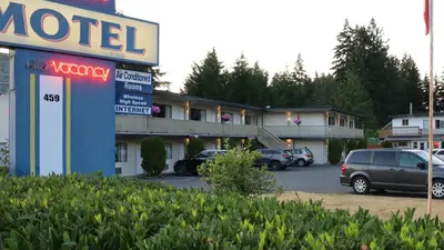 a motel sign with cars parked in a parking lot at Skylite Motel in Parksville