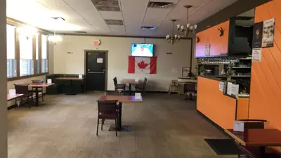 a restaurant with tables and chairs and a tv on the wall at Houston Motor Inn in Houston