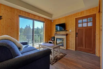 a living room with a couch and a fireplace at Newfie Seaside Retreat in Port Renfrew