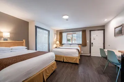 a hotel room with two beds and a table and chairs at Swiss Chalet Motel in Revelstoke