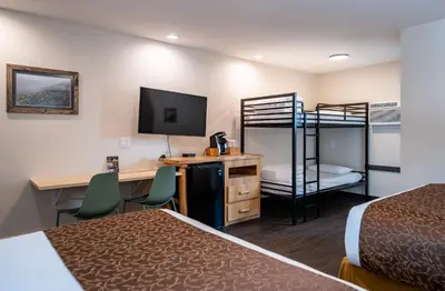 a hotel room with two beds and a desk and bunk beds at Swiss Chalet Motel in Revelstoke
