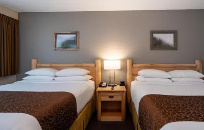 a hotel room with two beds and a lamp at Swiss Chalet Motel in Revelstoke
