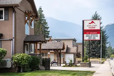 a house with a sign in front of a house at Swiss Chalet Motel in Revelstoke