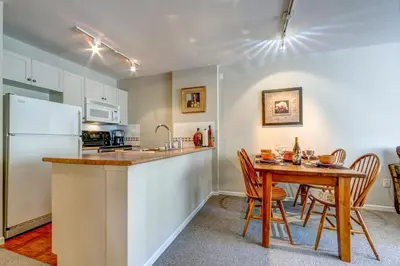a kitchen with a table and a white refrigerator at Town Plaza Suites by Golden Dreams in Whistler