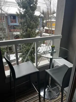 a balcony with a table and two chairs and a window at Town Plaza Suites by Golden Dreams in Whistler