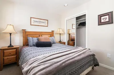 a bedroom with a bed and two lamps and a mirror at Town Plaza Suites by Golden Dreams in Whistler
