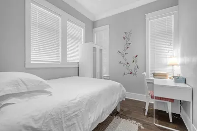 a white bedroom with a bed and a desk and windows at Vancouver West Cozy Retreat by Host Launch in Vancouver