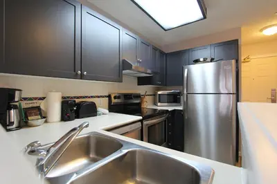 a kitchen with a stainless steel refrigerator and black cabinets at Marketplace Lodge by Whistler Retreats in Whistler