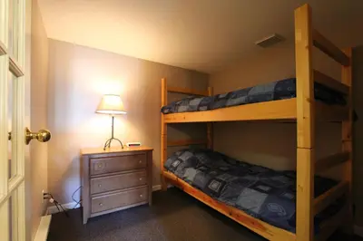 two bunk beds in a room with a lamp and a dresser at Marketplace Lodge by Whistler Retreats in Whistler