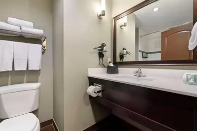 a bathroom with a toilet and a sink and a mirror at Best Western Pacific Inn in Vernon