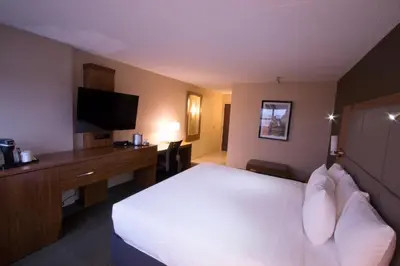 a hotel room with a large bed and a television at Ramada by Wyndham Northern Grand Hotel & Conference Centre in Fort Saint John