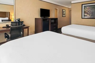 a hotel room with two beds and a desk at Best Western Plus Pitt Meadows Inn & Suites in Pitt Meadows