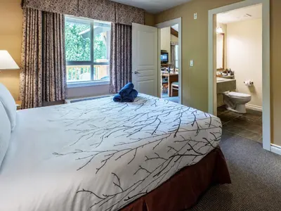 a bedroom with a large bed with a blue bag on it at Pemberton Valley Lodge in Pemberton
