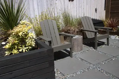 two chairs sitting in a garden with plants at Le Chalet Waterfront Retreat in Ucluelet