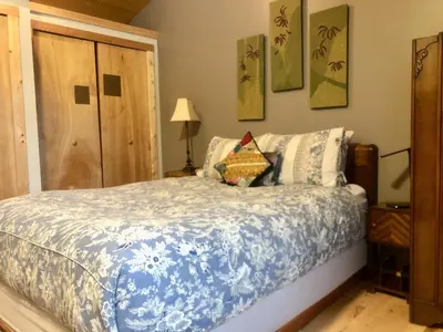a bedroom with a bed with a blue and white comforter at Morning Star Cabin in Nelson