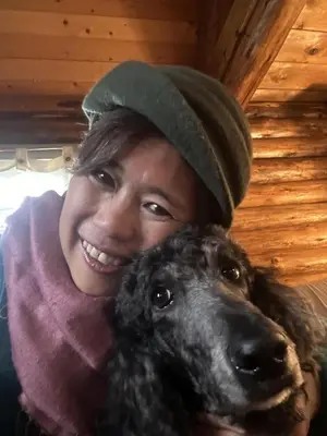 a woman is smiling with a black dog at Morning Star Cabin in Nelson