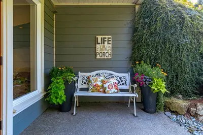a bench sitting on the side of a house with flowers at Shawnigan Suite B & B in Shawnigan Lake