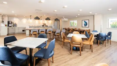 a restaurant with tables and chairs and a kitchen at Pomeroy Hotel Fort McMurray in Fort McMurray