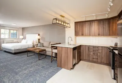 a kitchen and a living room with a bed at Pomeroy Hotel Fort McMurray in Fort McMurray