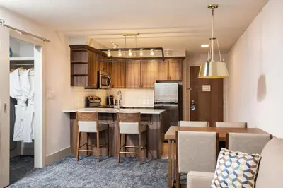 a kitchen with a bar and a dining room at Pomeroy Hotel Fort McMurray in Fort McMurray