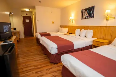 a hotel room with three beds and a flat screen tv at Canadas Best Value Inn- Riverview Hotel in Whitehorse