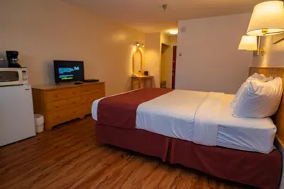 a hotel room with a large bed and a television at Canadas Best Value Inn- Riverview Hotel in Whitehorse