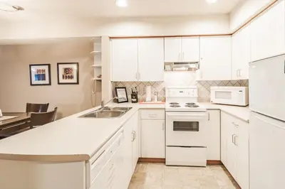 a kitchen with white cabinets and a sink at Lake Placid Lodge by Elevate Vacations in Whistler