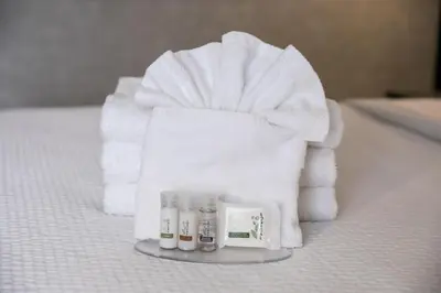 a pile of white towels and cosmetics on a bed at Days Inn & Suites by Wyndham Edmonton Airport in Leduc