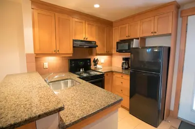 a kitchen with wooden cabinets and a black refrigerator at The Hidden Ridge Resort in Banff