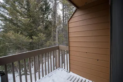 a balcony with a snowcovered bench on a deck at The Hidden Ridge Resort in Banff